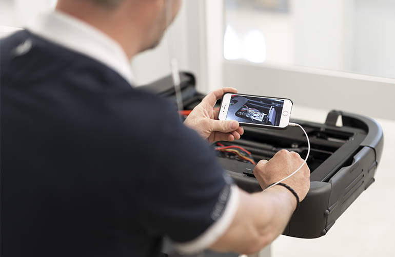 Un homme utilisant un téléphone portable pour filmer les rouages internes d’un produit.
