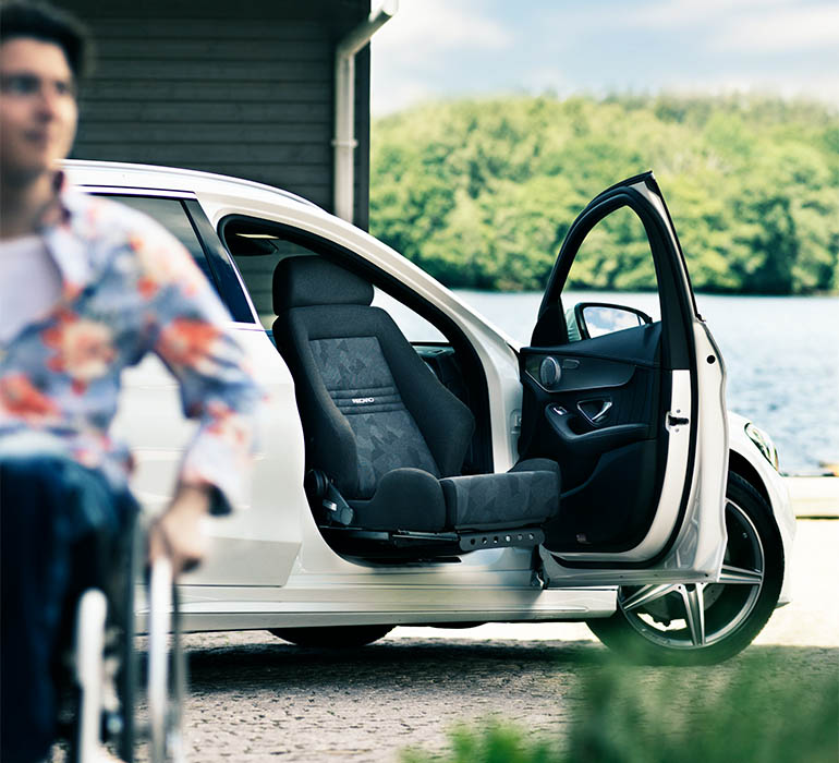 Person in wheelchair rolling away from a car.