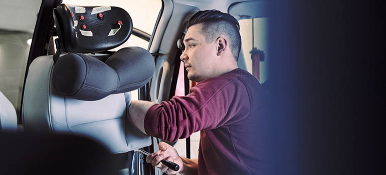 A vehicle adaptation technician working on a car seat. 