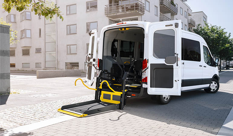 A van parked in a residential area with a wheelchair lift folded out from the back