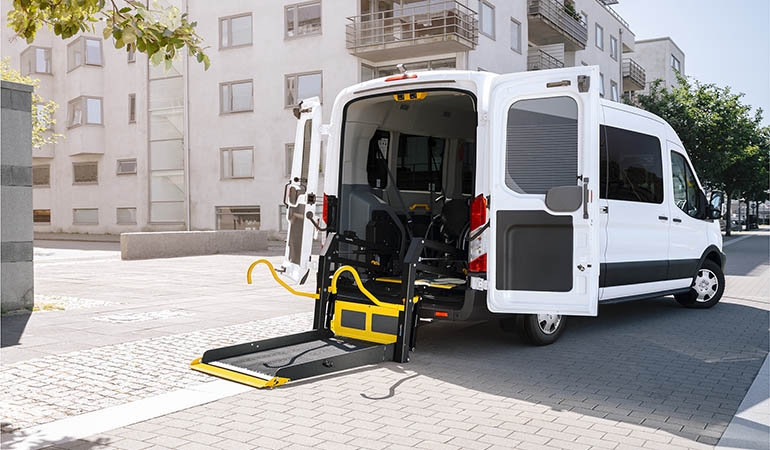 Une camionnette garée dans un quartier résidentiel avec un élévateur pour fauteuil roulant déplié à l'arrière