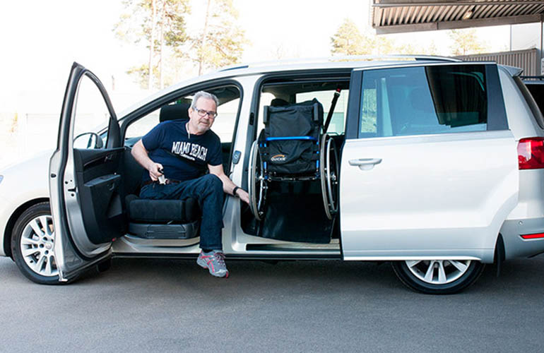 Man in the front seat of a van bringing a wheelchair into the middle section