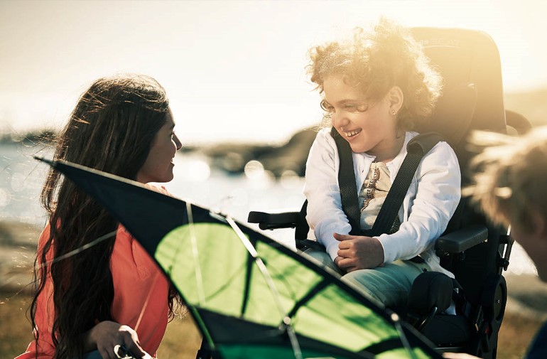 Woman smiling at child sitting in a wheelchair