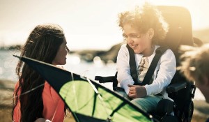 Woman smiling at child sitting in a wheelchair