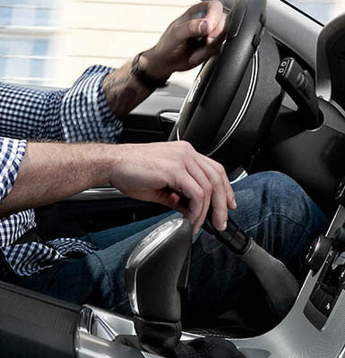 One hand holding a steering wheel and the other on a gas/brak hand control lever. 