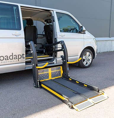 A deployed wheelchair lift in the side door of a van. 
