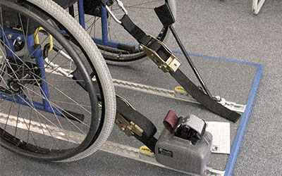 Historic photo showing an early model of wheelchair tie-downs.