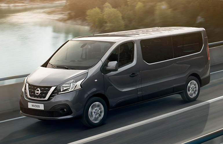 Grey Nissan van driving beside a lake