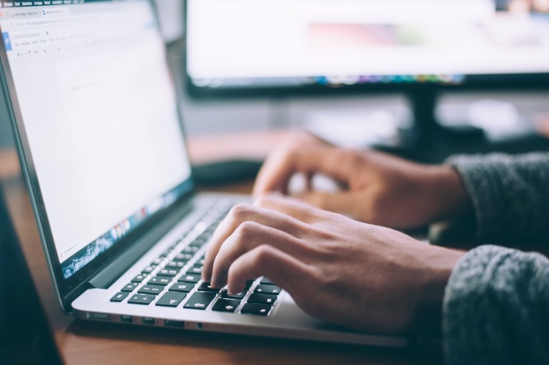 Mains en train de taper sur le clavier d’un ordinateur portable.