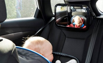 Baby in a car seat looking at a rear view mirror