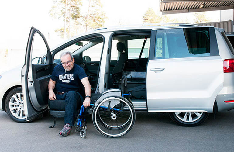 Mann, der von einem Rollstuhl in einen Van einsteigt