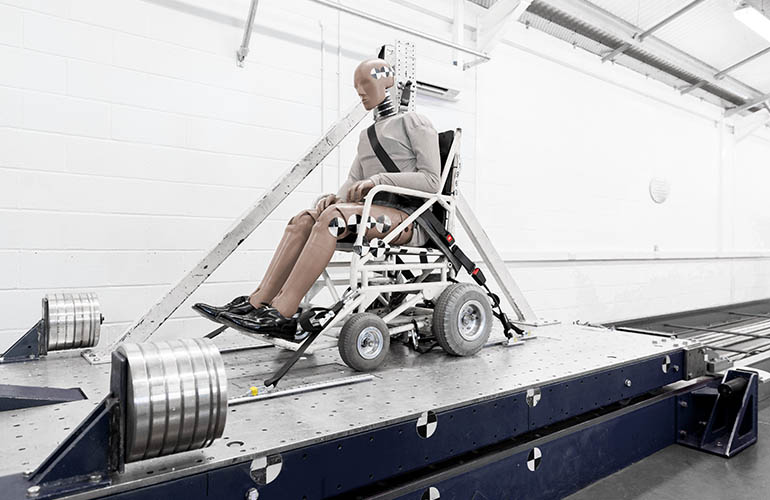 Ein Crashtest-Dummy im Rollstuhl auf einem Testschlitten.