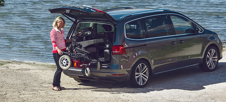 Frau, die einen Carony-Klassiker in den hinteren Kofferraum eines Autos hebt