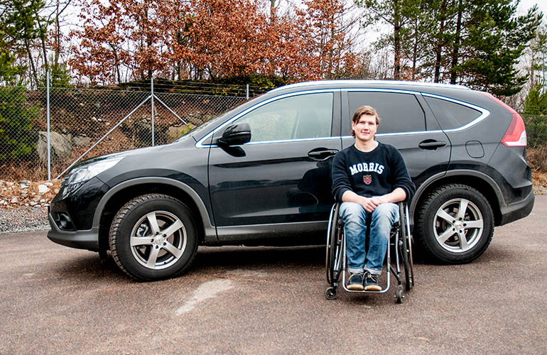 Man sitting in a wheelchair outside a car