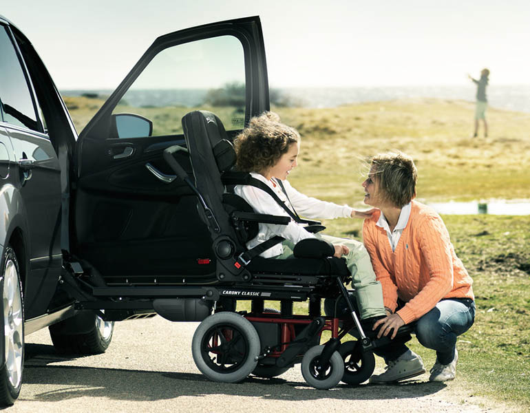 A girl seated in a GS seat on a Carony talking to a woman that is crouching down.