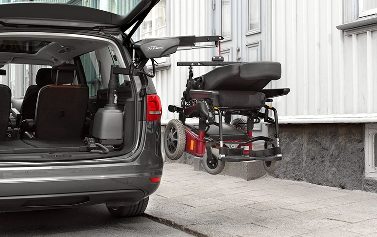 Elektrorollstuhl, der von einem Rollstuhlzug in einem Auto hängt.