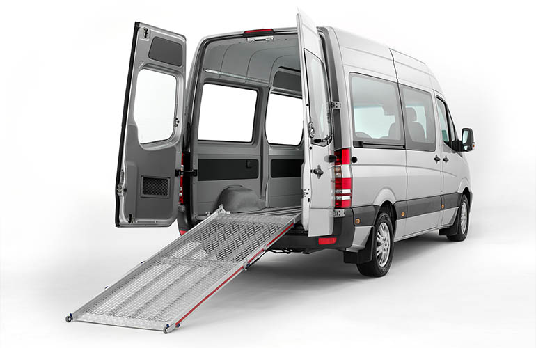 A large van with open rear doors and a deployed ramp. 