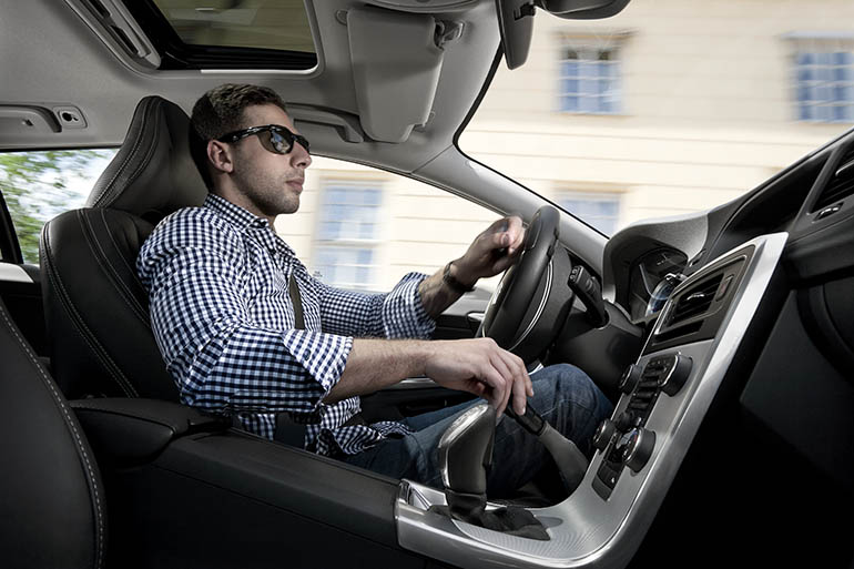 A young man driving a car seen from the passenger seat. 