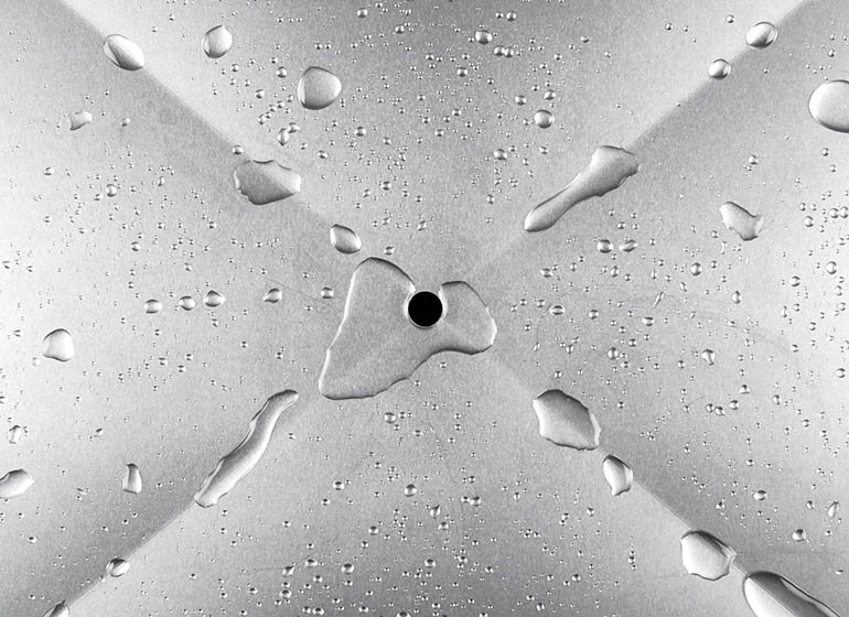 Water droplets on metal running towards a hole in the center.