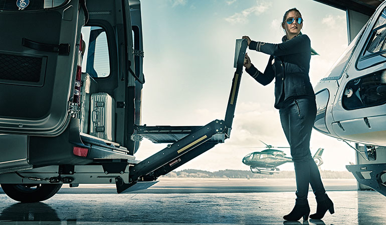 A female bus driver unfolding a BraunAbility A-Series wheelchair lift. 