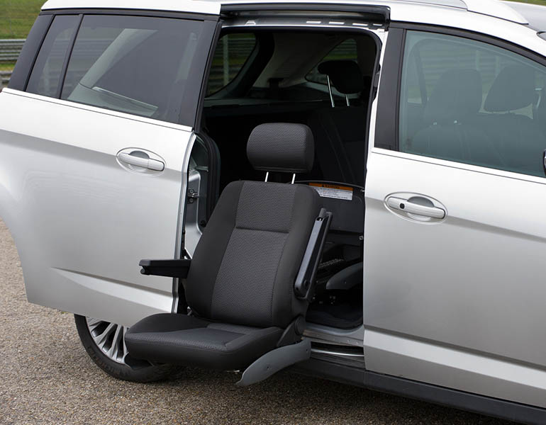 The compact seat on a swivelled out seat lift installed in the second row of a minivan.