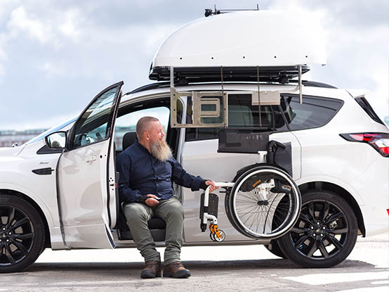 Mann lädt seinen Rollstuhl in die Chair Topper Dachbox