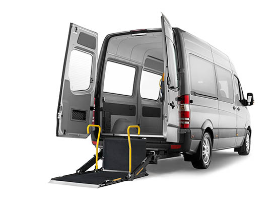 Une camionnette argentée avec les portes arrière ouvertes et une plateforme élévatrice pour fauteuil roulant A-Series déployée au sol.  