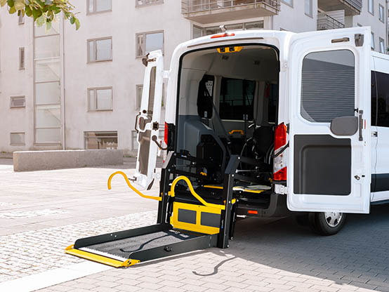 Une camionnette avec des portes arrière ouvertes et un élévateur pour fauteuil roulant déployé.