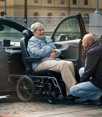 Man assisting woman into a car with a Carony