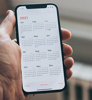 Eine Hand, die ein Smartphone hält, das eine Kalender-App zeigt.