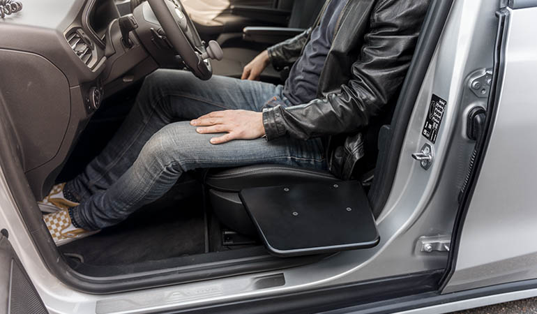 A man sitting in the driver's seat with a transfer board folded out next to him