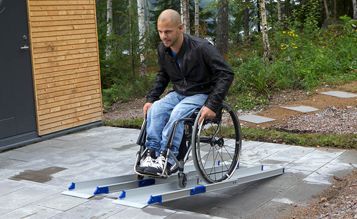 Man on a wheelchair rolling up a ramp