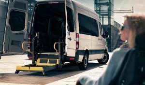 Woman sitting outside a van with a lift lowered from the rear door