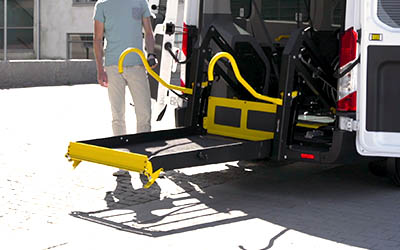 Man lowering a lift installed on the rear end of a van