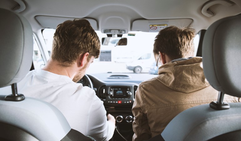 Two people in a car adjusting the radio. 