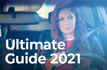 Le texte "Ultimate Guide 2021" superposé sur une vue à travers un pare-brise d'une femme au volant d'une voiture.