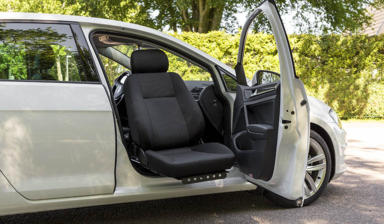 A parked car with the car seat swiveled out on the passenger side.