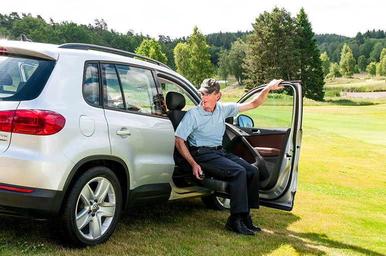 Älterer Mann, der einen Sitzlift benutzt, um ein Fahrzeug auf einem Golfplatz zu verlassen.